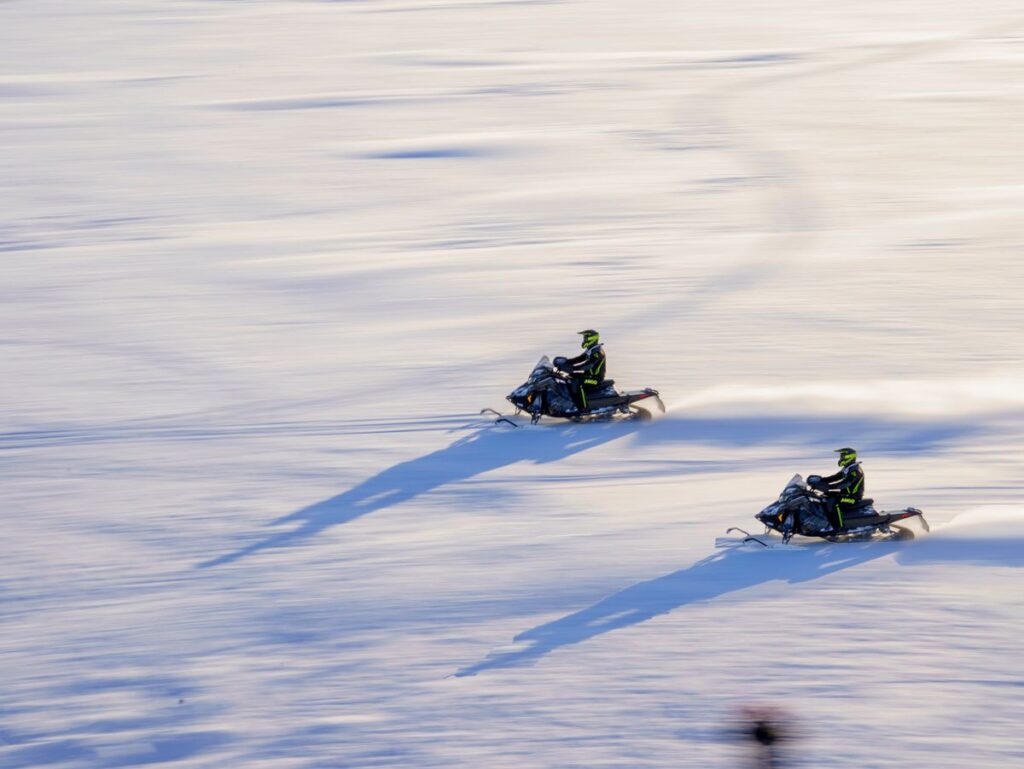 Δύο snowmobile διασχίζουν χιονισμένο τοπίο στη Λαπωνία